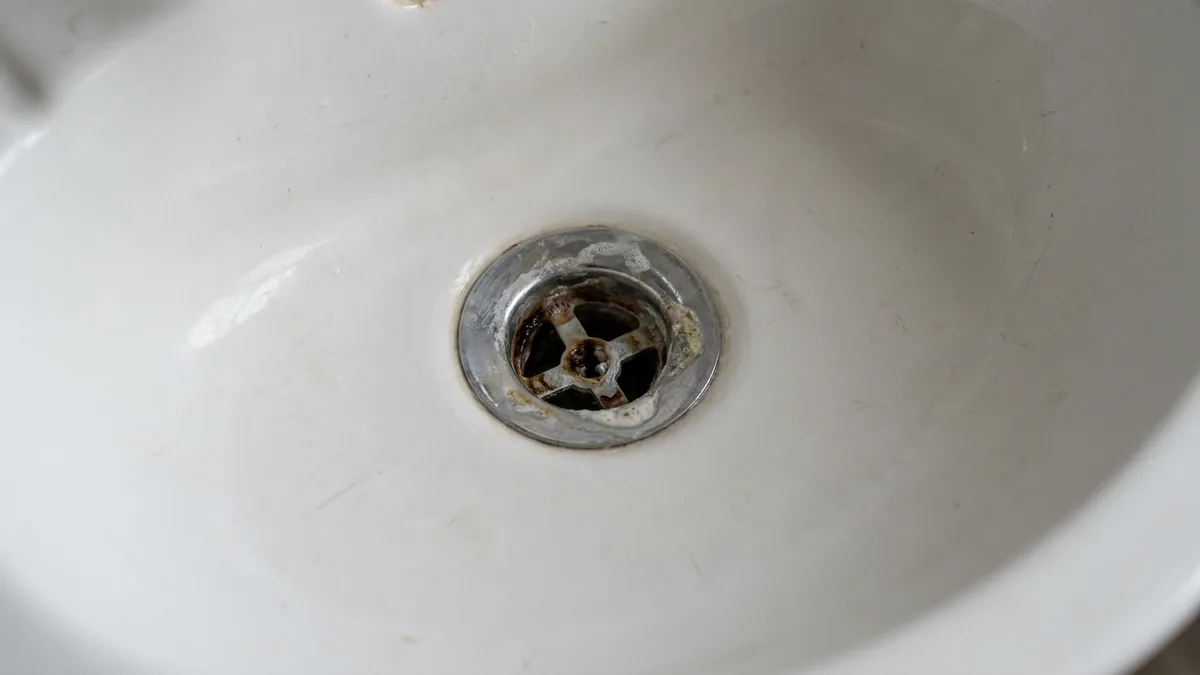 Close-up of a bathroom basin drain, a common source of smelly drains