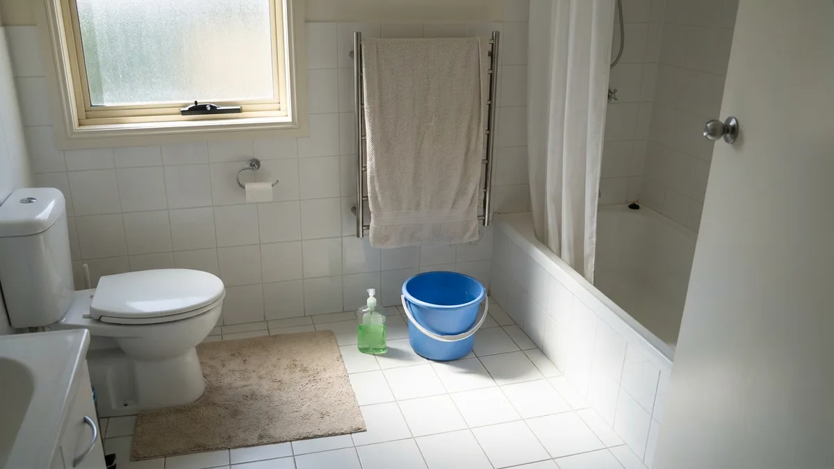 A toilet with a bucket of water and dish soap beside it, ready to unclog a toilet without a plunger